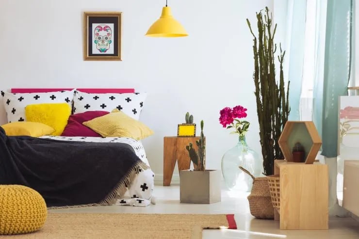 Sugar skull painting in gold frame and king-size bed with colorful pillows in artistic bedroom