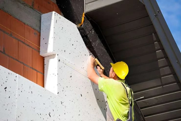 A construction worker insulates a building with styrofoam